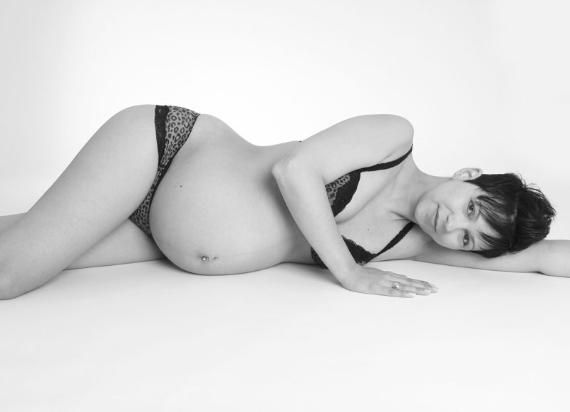 Schwangerschaftsfotografie Detmold - Silvia Stolzenberg Motiv: schwangere Frau in sw auf dem Boden liegend